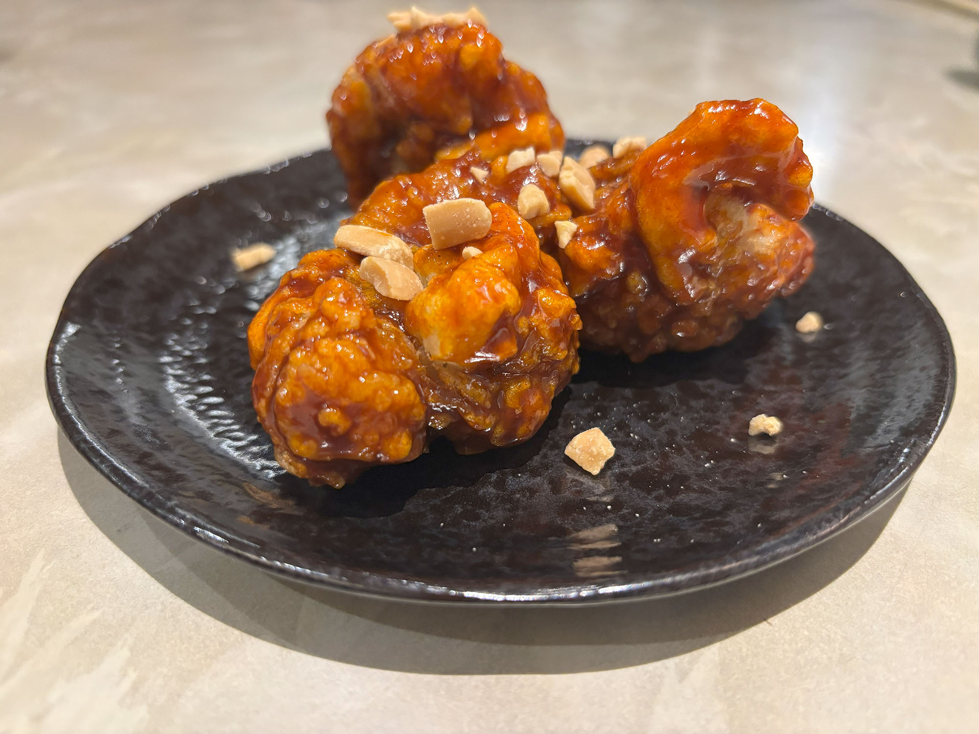 【 ヤンニョムチキン 】（660円）
韓国グルメ好きにはたまらないヤンニョムチキン！
甘辛のタレがしっかり絡んでいて、一口食べるとじゅわっとした旨みが広がる。さらに、トッピングのナッツがカリカリっとしていて、食感のアクセントに。ピリ辛好きな人にもおすすめ！